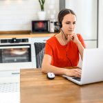 Young woman works from home using headset laptop 75293117 75419015